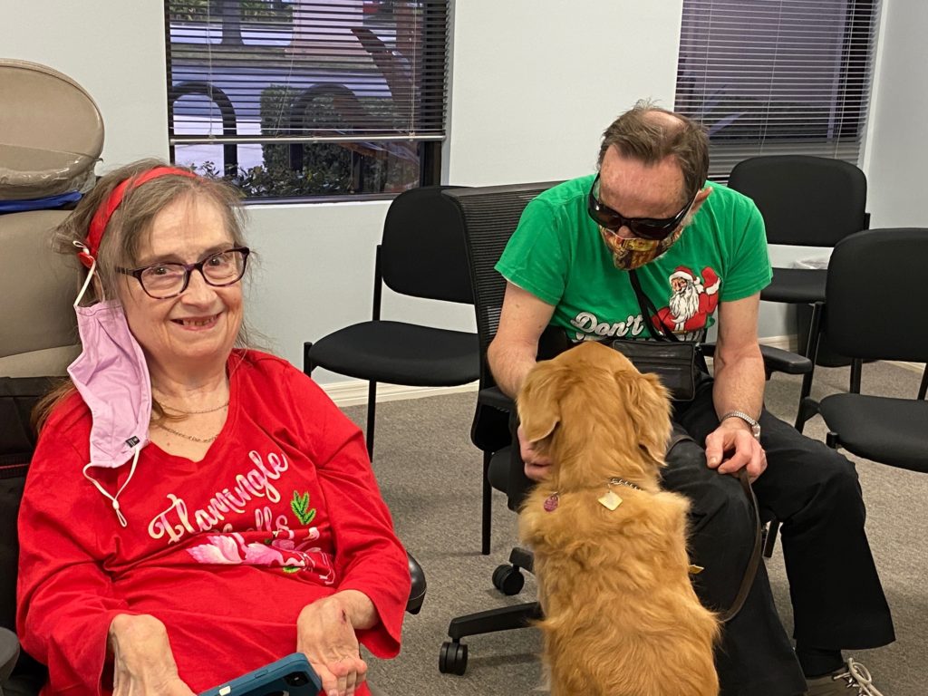 Nancy Burgess Hall smiling and Doug Hall looking at Watson his golden retriever 