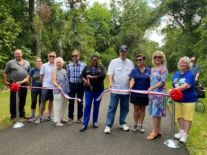 10 people in a line with Barbara Girtman cutting the ribbon for the new trail 
