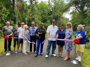 10 people in a line with Barbara Girtman cutting the ribbon for the new trail